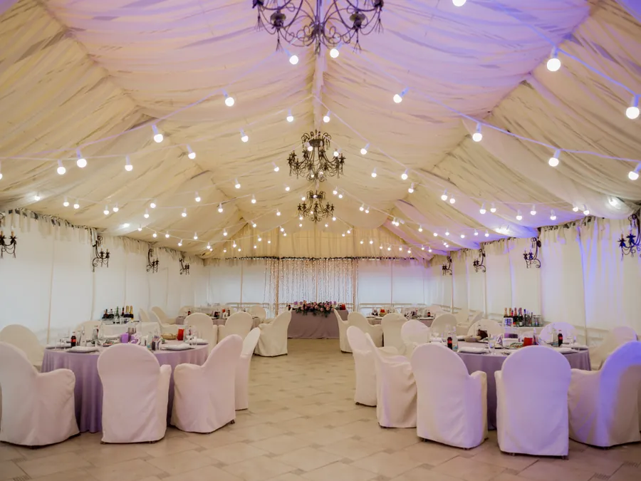 Nettoyage événementiel : salle de réception sous chapiteau, tables dressées et chaises housse avant l'arrivée des invités
