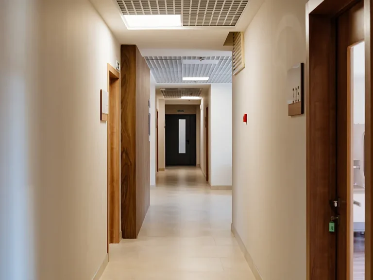 Nettoyage des parties communes : couloir d'immeuble impeccable, sol clair, portes en bois et éclairage au plafond