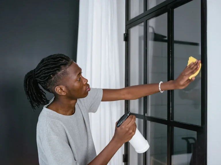 Nettoyage de vitres : homme essuyant une vitre à cadre noir avec une éponge jaune